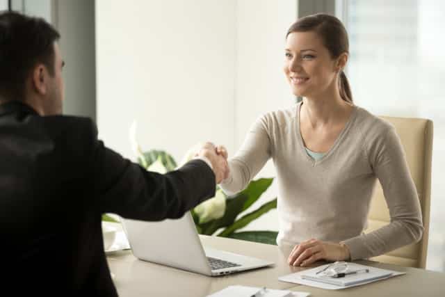 Female employee handshaking with male client